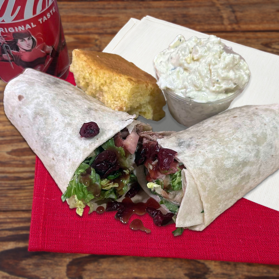 Northwoods Smokin' BBQ wrap with cranberries, lettuce, and sauce, served with cornbread and coleslaw.